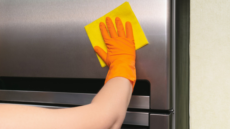 rubber glove and sponge rubbing stainless steel fridge