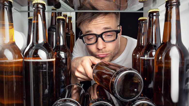 man grabbing beer bottle inside fridge