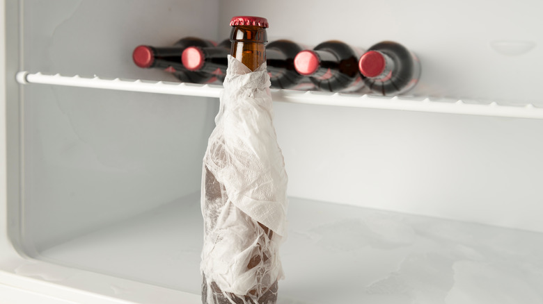 wet kitchen towel around bottle in freezer