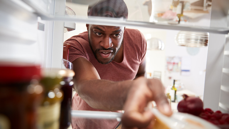 man reaching to back of fridge