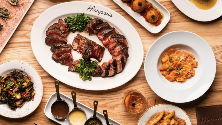 steak, pasta and sides on white harper's logo plate