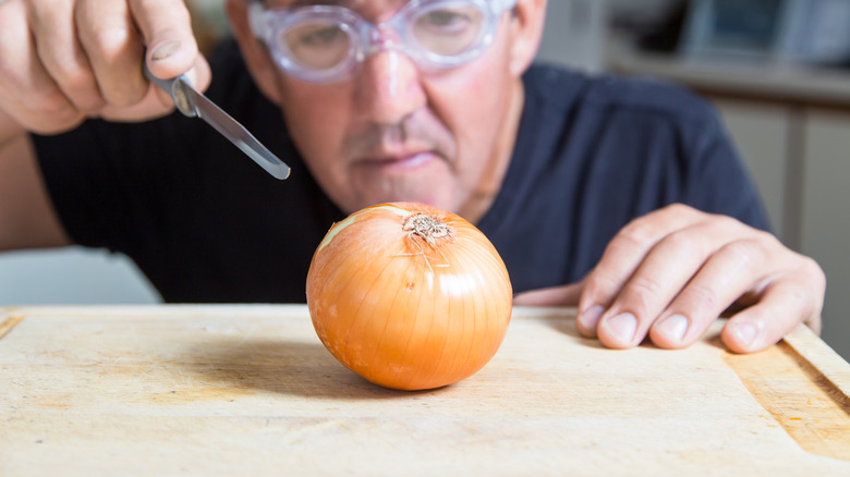 man with goggles cutting onion