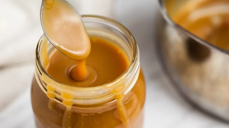 spooning caramel sauce into jar