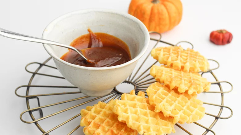 bowl of pumpkin caramel sauce with spoon and waffles on side