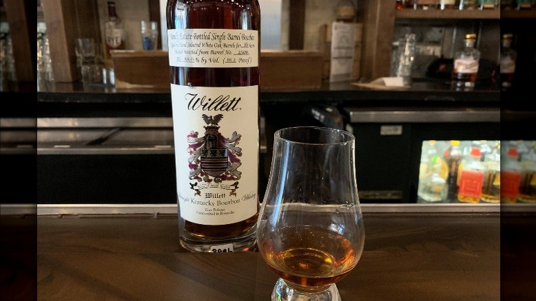 bottle of Willett next to a whiskey glass full of bourbon 