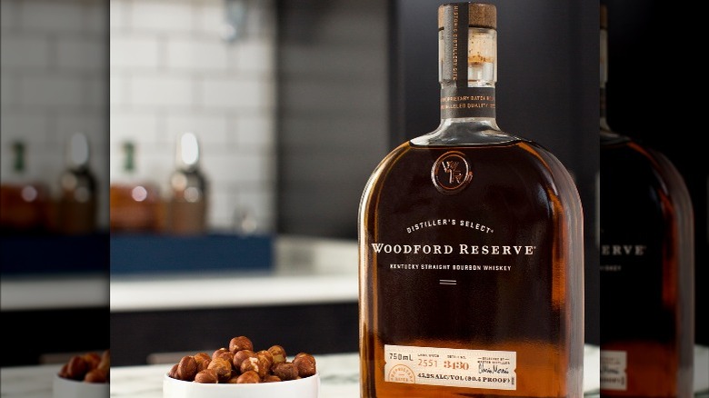 bottle of Woodford Reserve on a table next to a bowl of nuts