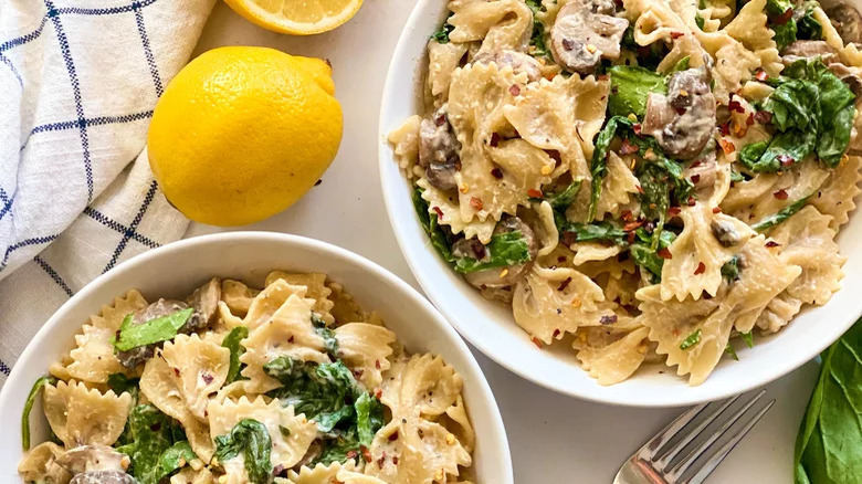 bowls of creamy spinach pasta with lemons and fork
