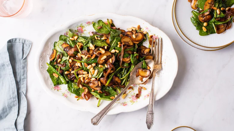 fancy plate with wilted spinach salad and fork and spoon