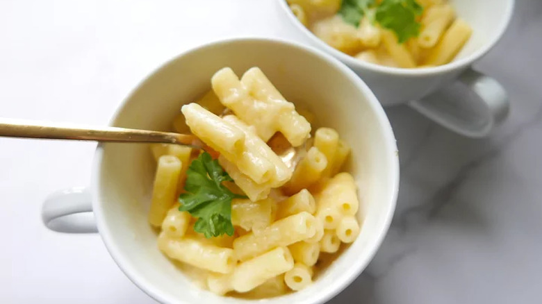 White mugs with macaroni and cheese and a spoon