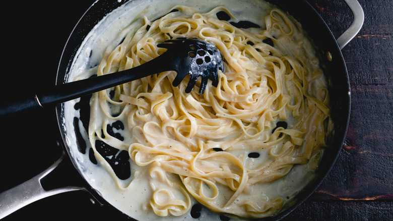 past in pan with pasta spoon and creamy sauce