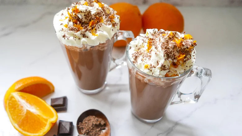 Hot chocolates with whipped cream and oranges