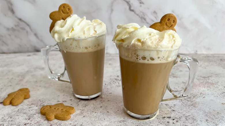 Two gingerbread lattes with whipped cream and cookies