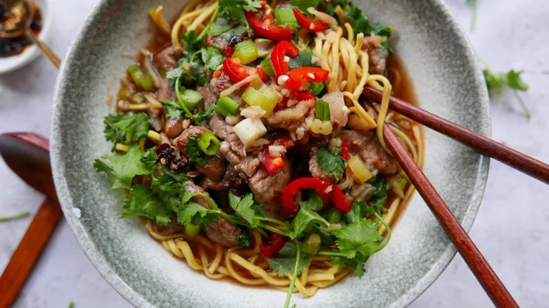 Beef and noodles in broth in a bowl with chopsticks