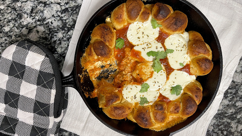 bread knots, cheese, and tomato sauce in a black frying pan