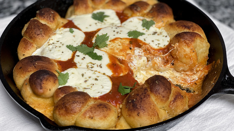 bread knots, cheese, and tomato sauce in a black frying pan