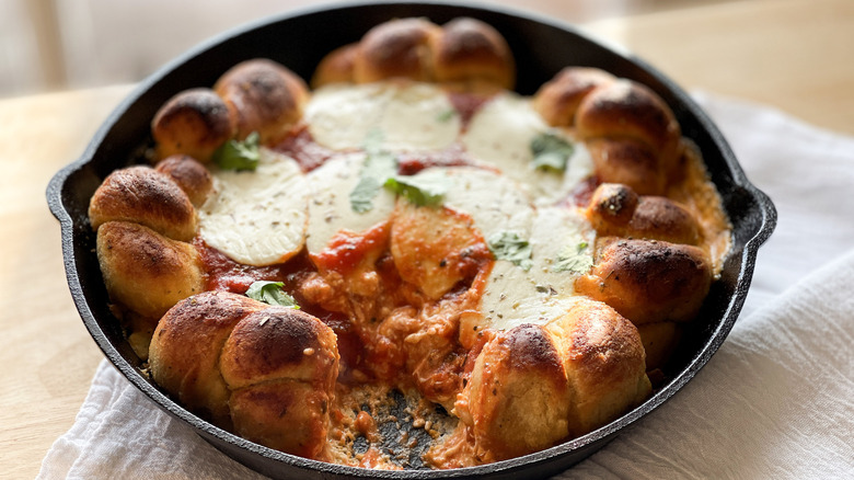 bread knots, cheese, and tomato sauce in a black frying pan