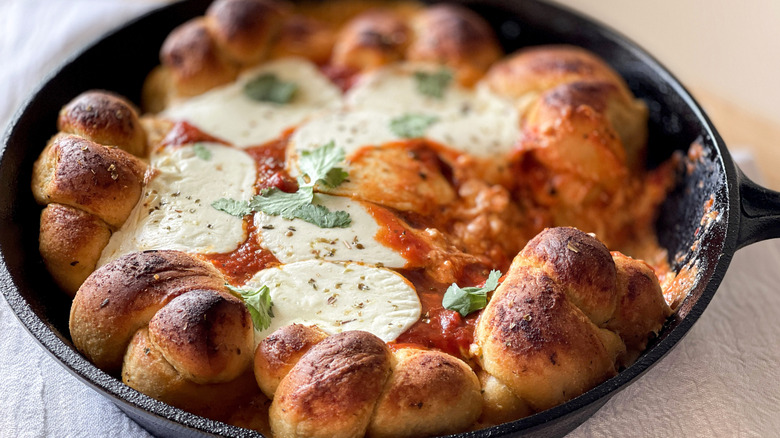 bread knots, cheese, and tomato sauce in a black frying pan