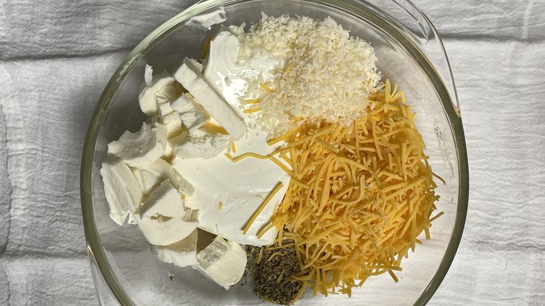 four types of cheese and dried oregano in a clear bowl