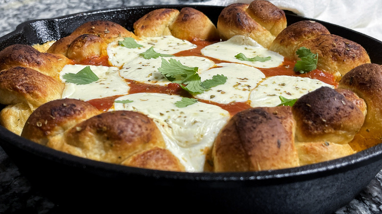 bread knots, cheese, and tomato sauce in a black frying pan