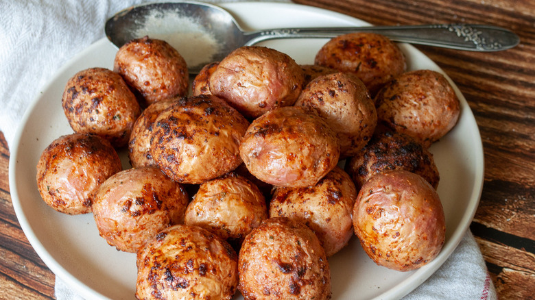 3 ingredient air fryer ranch potatoes sitting on a white plate near a metal spoon with Hidden Valley Ranch dry seasoning mix