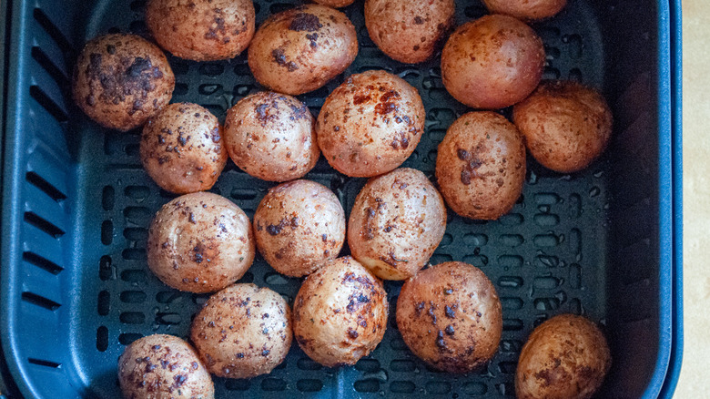 air fryer basket full of seasoned baby red potatoes