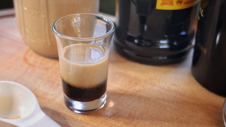 a shot glass with a layer of coffee liqueur topped by a layer of cream liqueur