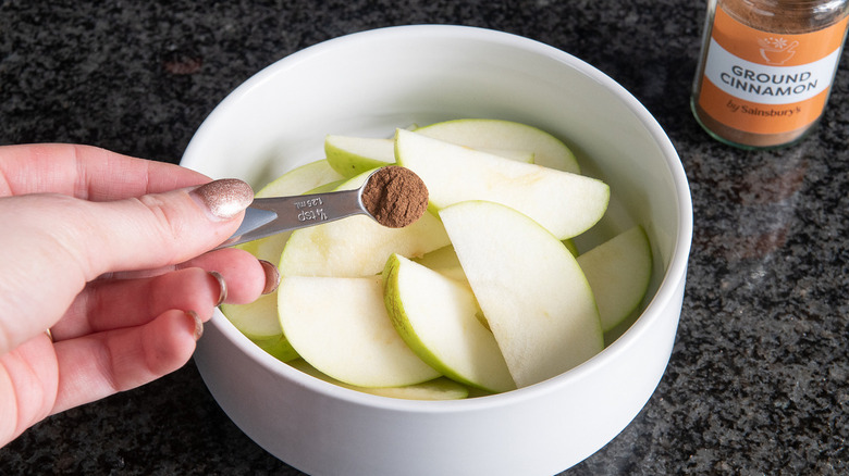 cinnamon being sprinkled over apples