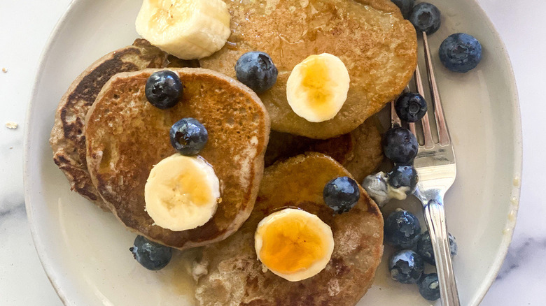 Pancakes, blueberries, and banana slices sitting on a plate