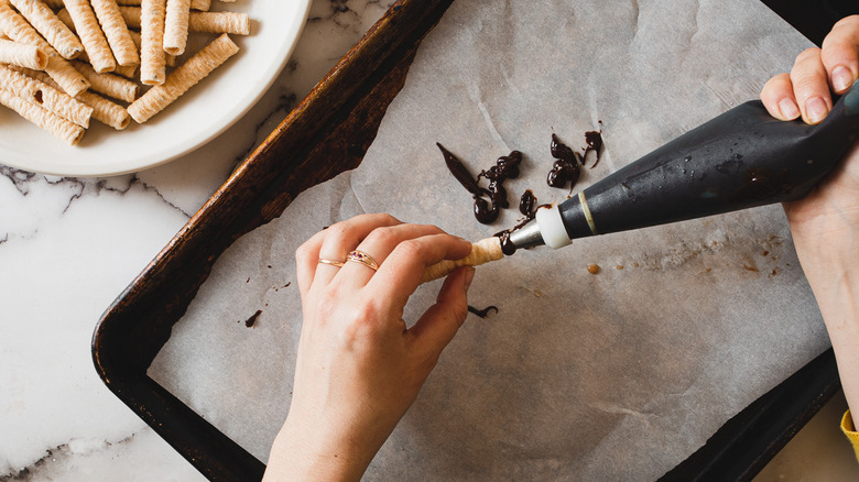 piping chocolate ganache into Pirouette cookies