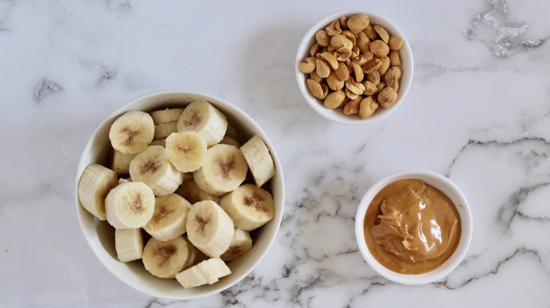 Bananas, peanuts, and peanut butter on white marble