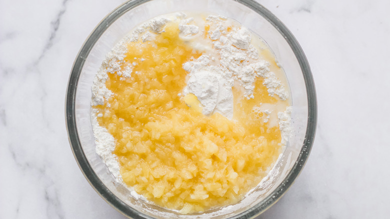 A clear bowl filled with crushed pineapple and angel food cake mix