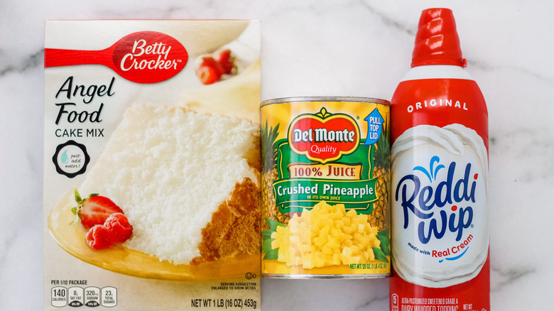 A box of cake mix next to a can of crushed pineapples and a can of whipped cream