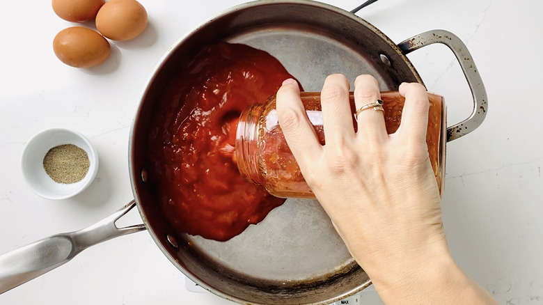 pouring pasta sauce into pan