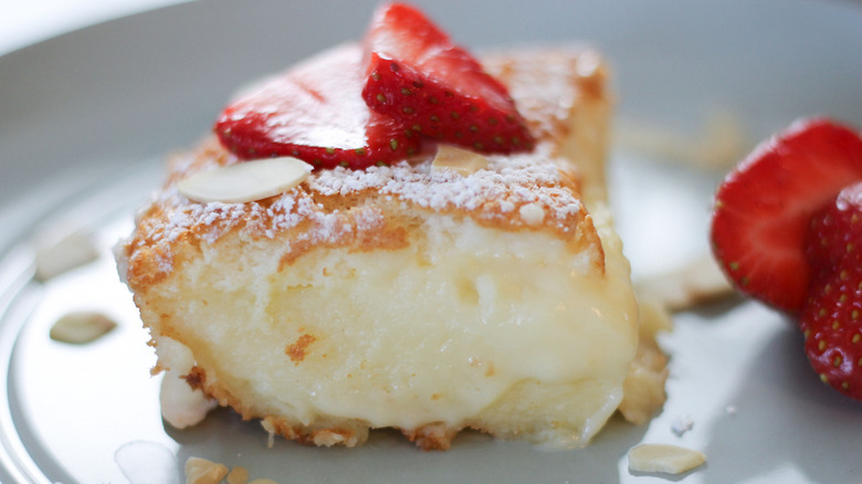 3-Layer Magic Cake slice on cake with strawberry slices and almonds