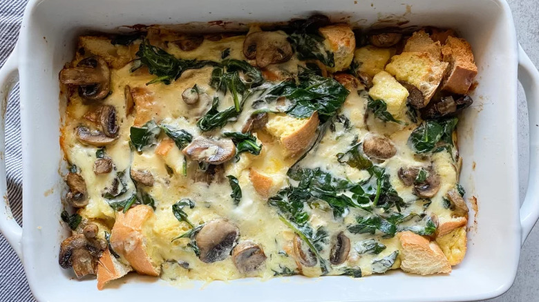 White baking dish with baked bread and spinach strata. 