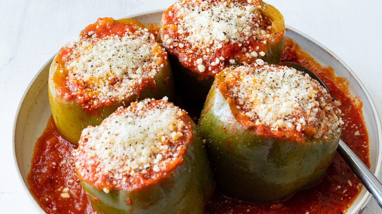 Four bell peppers with meat and cheese stuffing in sauce.