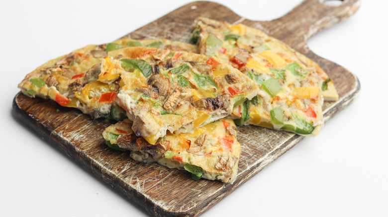 Wedges of veggie and mushroom frittata on a cutting board. 