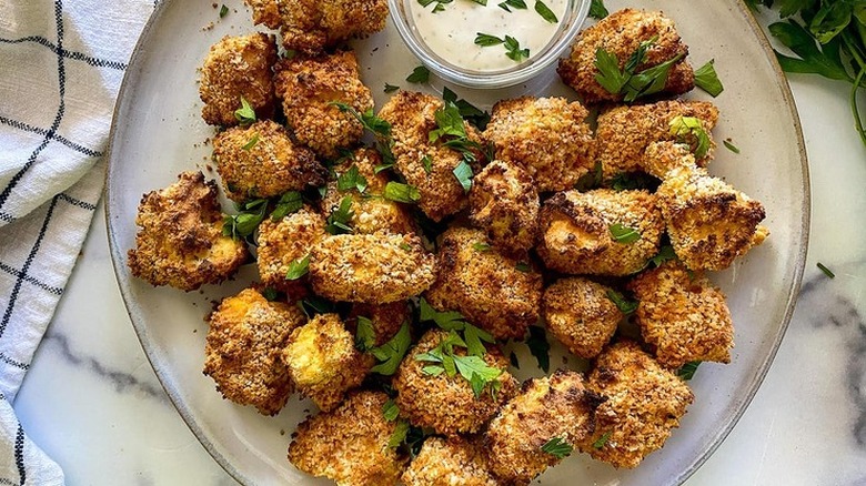 Plate of fried, breaded tofu pieces with dipping sauce. 