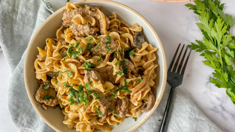 Shallow bowl with egg noodles and beef in creamy sauce.