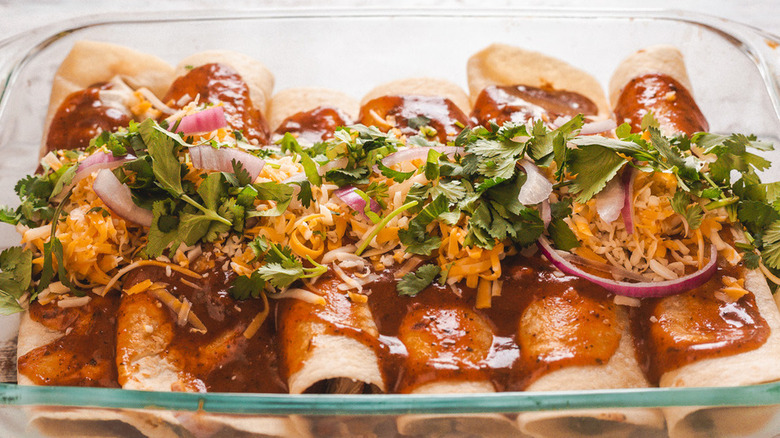 Rolled up enchiladas with cheese and herbs in glass pan. 