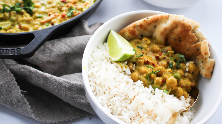 Chickpea stew in pan and in bowl with rice and naan bread. 