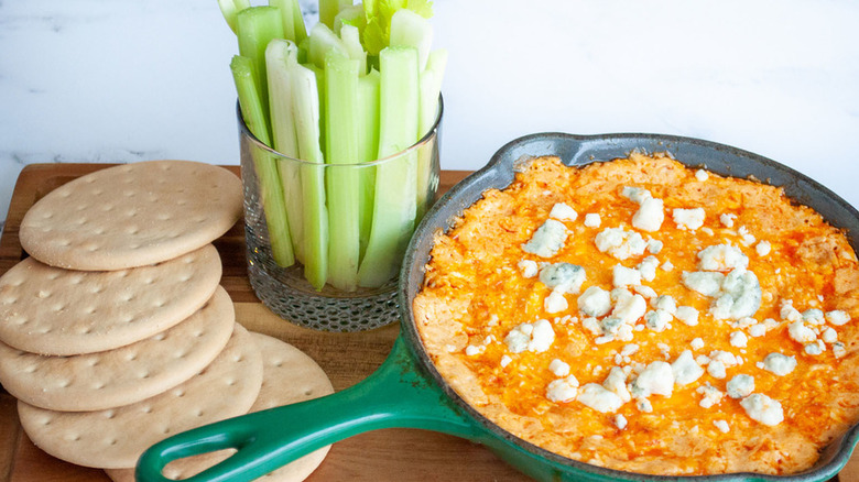 A pan of dip with bread and cucumber sticks