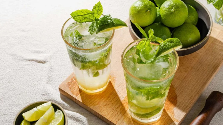 Mojito drinks in glasses with mint leaves and limes.