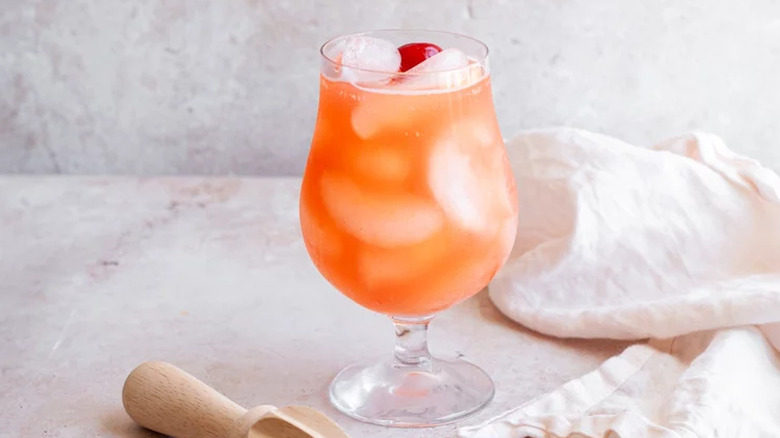 Pink-orange drink with ice in a cocktail glass. 