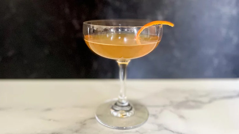 Coupe glass with orange cocktail and orange peel.