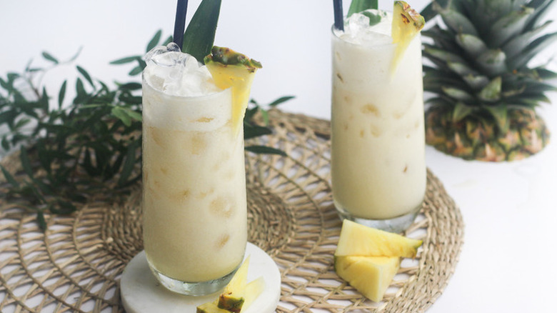 Tall glasses with creamy white drink and pineapple wedge