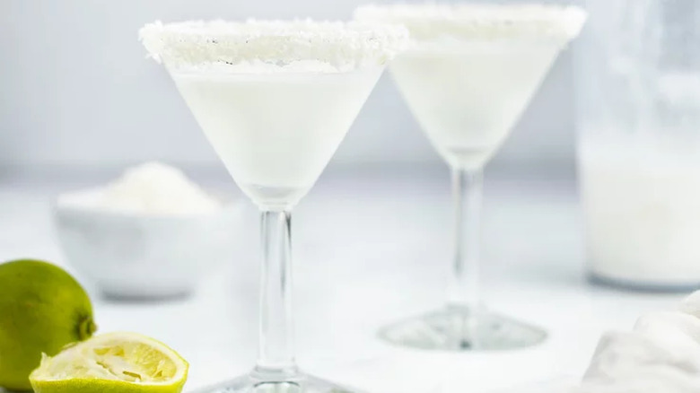 Cocktail glasses with frosty drinks and coconut-coated rims. 