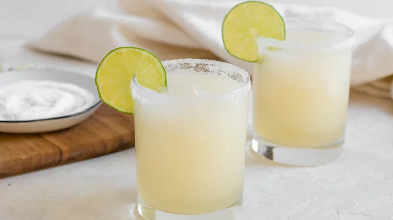 Small glasses with slushy cocktails, salt rims, and lime slices.