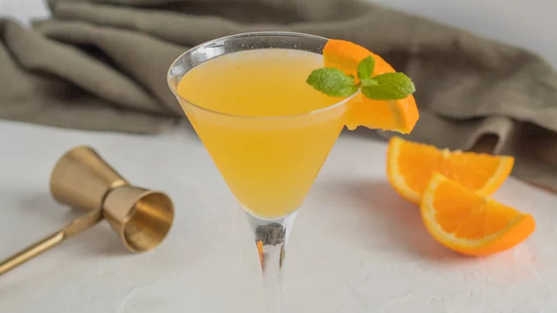 Orange drink in martini glasses garnished with mint leaves.