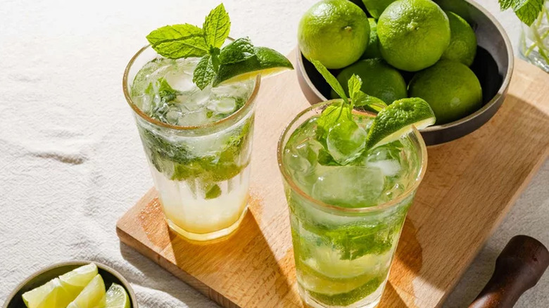 Glasses with mint leaves, limes, and soda.